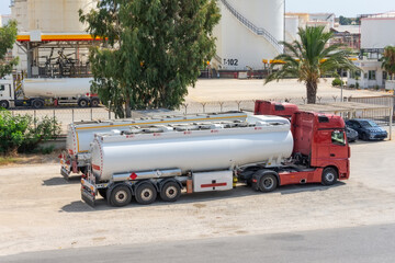 Parking row of trucks with fuel tanks of a warehouse and storage of huge tanks of raw material...