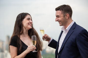 Happy businesspeople enjoy talking together at the office event. Man and woman with champagne smiling and laughing at business meeting party. People flirting while joining corporate activities
