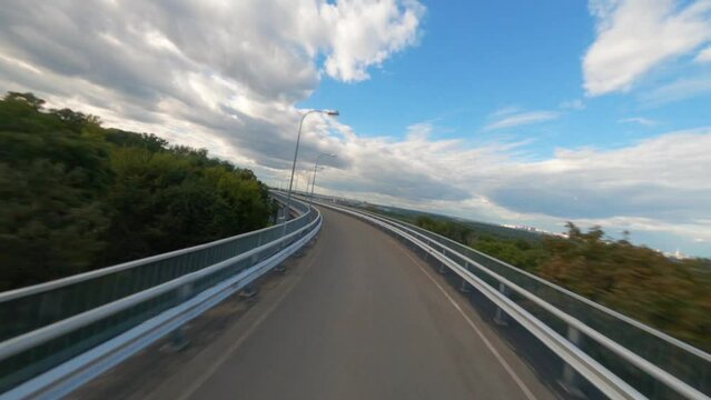 FPV drone flying along the road, Aerial view of road and city, Kiev, Ukraine, Park Bridge Mariinsky Park Kiev Ukraine Landmark, Green grass hill in foreground. Sidewalk neatly laid over the hill