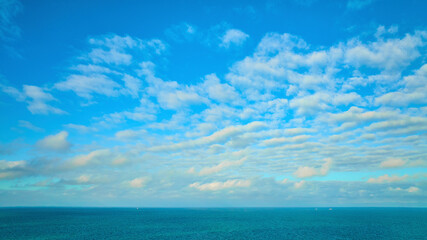 Fototapeta na wymiar Blue sky with wispy white clouds, dream and inspiration over blue Lake Michigan water, inspire