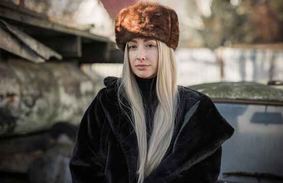 Slavic bimbo aesthetic. Portrait of a European type Blond head Young woman with natural skin in fur unisex hat.  