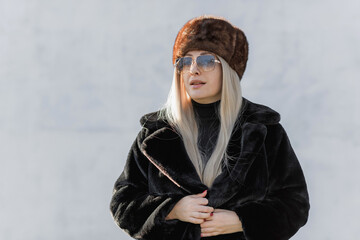 Slavic bimbo aesthetic. Portrait of a European type Blond head Young woman with natural skin in fur unisex hat.  