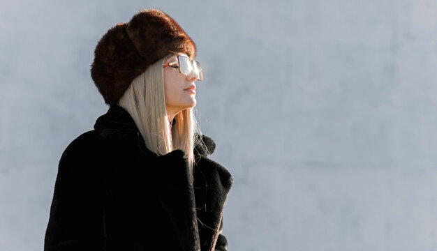 Slavic bimbo aesthetic. Portrait of a European type Blond head Young woman with natural skin in fur unisex hat.  