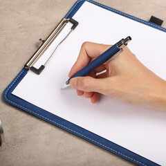 Colorful leather clipboard. Genuine leather clipboard, concept shot, top view, different color, woman about to write a note on empty blank with a pen.