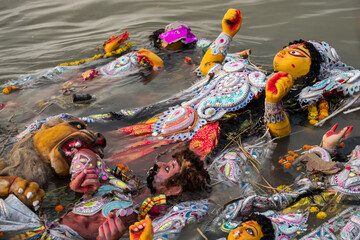 Immersion of idol goddess durga in river after completion of four days festival. Durga is created by clay. - obrazy, fototapety, plakaty