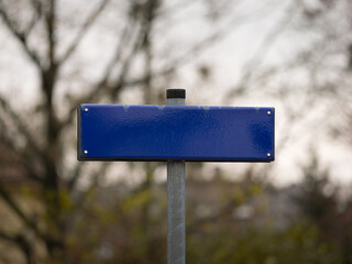 Empty road name signage template. The blank space can be used as a mockup. The street name was removed and a blue metal plate remains. A location in Germany is typically printed on the sign.
