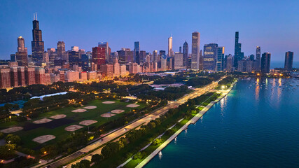 Fototapeta na wymiar Aerial Chicago park at night with city lights and sunset glow over buildings with Lake Michigan, IL