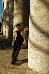 Handsome Italian Caucasian boy dressed well climbs the stairs for photo shooting. The man looks or...