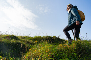 Latin woman with backpack climbing a hillside while hiking in a beautiful Irish landscape