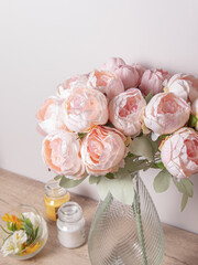Artificial flowers for the interior. Bouquet of pink peonies in a glass vase. Flowers in living room or bedroom