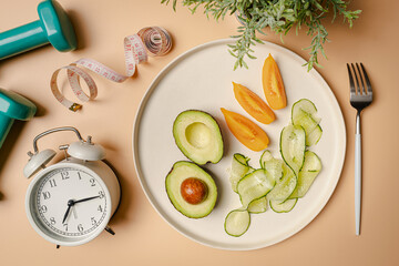 Creative flat lay composition with plate, alarm clock, knife, fork, dumbbell and measuring tape on...