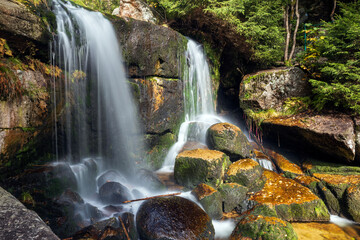 Fototapeta na wymiar Waterfall in the autumn forest. Long exposure photo. Beautiful nature background.