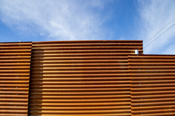 Rusty corrugated metal fence against a blue sky