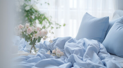 Cozy light white Bedroom with flowers and candles. pillows, duvet on a bed. Blue bed linen on a blue sofa. Bedroom with bed and bedding. Blurred view of light bedroom with big window