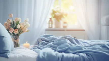 Foto op Plexiglas Cozy light white Bedroom with flowers and candles. pillows, duvet on a bed. Blue bed linen on a blue sofa. Bedroom with bed and bedding. Blurred view of light bedroom with big window © Bogdan