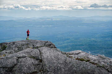 Trail runner over the horizon, standing at the top of Morios mountain of a summer day, Charlevois, QC, Canada