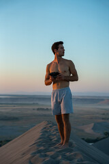 Man flying drone from top of sand dunes at sunset.  Located in the western part of the United States.  Person enjoying the view during a beautiful setting sun.