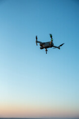 Drone flying in the air with blue sunset sky in background.  Beautiful sky with drone in foreground.