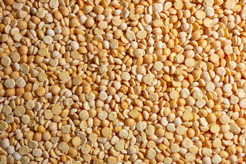 Uncooked Polished Split Peas Background. A Culinary Canvas of Dry Yellow Peas, Creating a Lively and Textured Background for Gourmet Cooking. Scattered Raw Polished Peas. Healthy Eating Ingredients