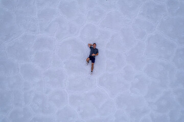 Aerial top down of man laying in Utah Salt Flats.  Shot on a drone.  Blue cracked salt flat near Salt Lake City, Utah in the western part of the United States.