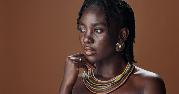 Face of black woman, skincare or model thinking of wellness, necklace or healthy beauty in studio. Dermatology, dreadlocks or African person with glow, idea or natural aesthetic on brown background