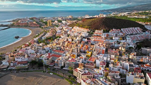 Aerial view of Los Cristianos one of Tenerife's most popular tourist resorts and luxury hotels. View from above of colourful houses with tiled roofs and wooden balconies in the Canary Islands, Spain.