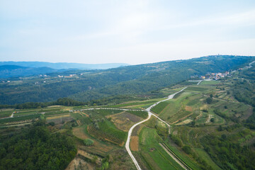 Panoramic aerial view of the picturesque countryside in a mountainous area with settlements, infrastructure, vegetable gardens and vineyards. Morning, shot from a drone.