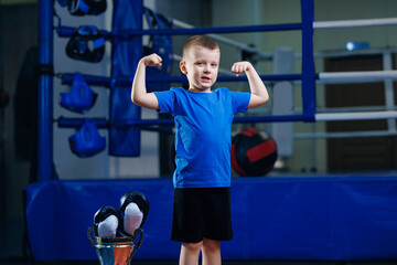 Boxer boy in black boxing gloves is training in ring sport gym for kid