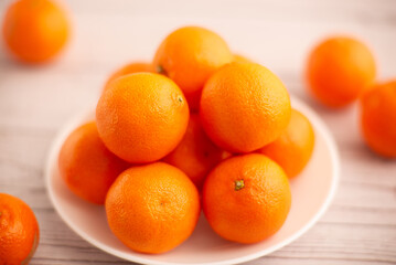 Mandarins arranged on a plate against a light surface, exemplifying the goodness of fruits