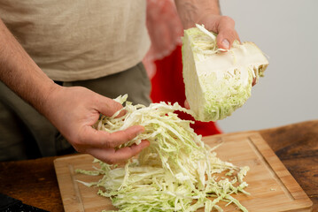 Preparing white cabbage on a bamboo board, cooking process detail.