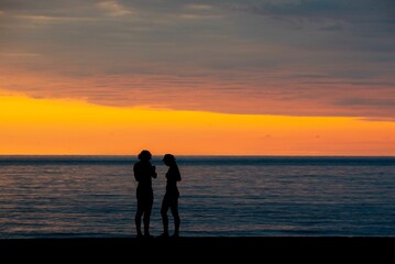 Two silhouettes on the background of a yellow-red sunset