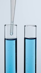Two glass tubes on a white background. The test tubes are filled with blue liquid, a pipette is lowered into one of them. Concept of medicine, biochemical research. Close up