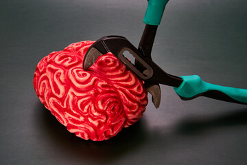 Red brain compressed by pliers. Concept of mental stress.