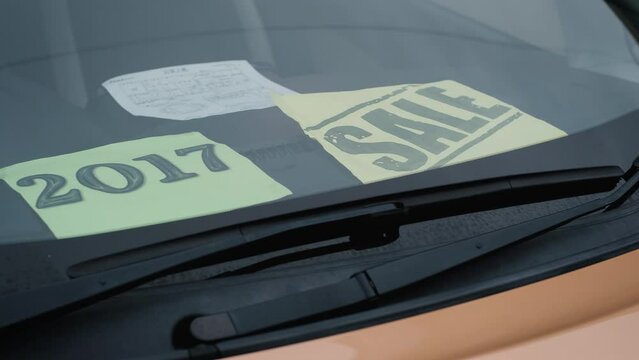 Used car with Sale sign on windshield, close-up