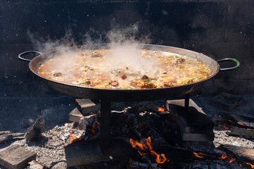 Paella, a traditional and famous Valencian food cooked with wood - 696551555
