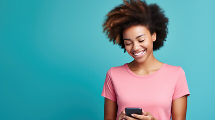 Young woman smiling and holding her smartphone on a blue background - obrazy, fototapety, plakaty