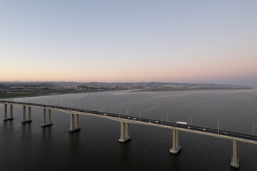 sunset over the ocean and second longest in europe bridge with cars driving vasco da gama in lisbon portugal