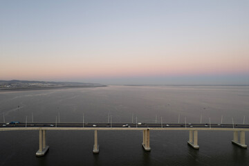 sunset over the ocean and second longest in europe bridge with cars driving vasco da gama in lisbon portugal