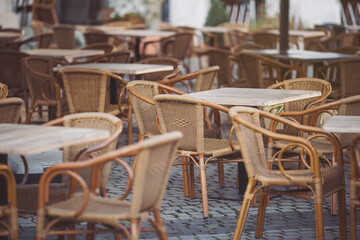 Fototapeta na wymiar Coffeehouse cafe restaurant terrace. Wooden chairs and tables. Outdoor terrace concept. Shallow focus. Copy space. Old fashioned empty cafe terrace with vintage chairs and tables. Loft style cafe.