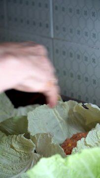A person wraps balls of minced meat on cabbage leaves, spanish food, "puchero" balls.