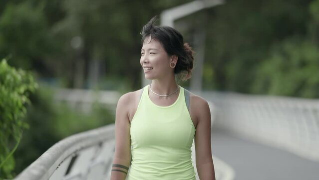 happy and smiling young asian woman walking relaxing in park while exercising outdoors