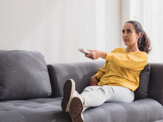 Portrait latin american woman one person smile happy sitting sofa and looking television hand...