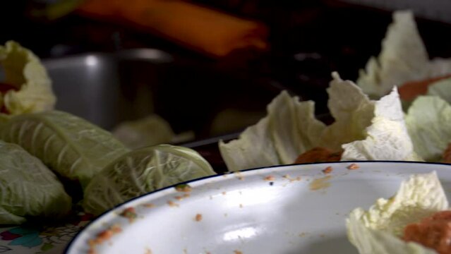 A person wraps balls of minced meat on cabbage leaves, spanish food, "puchero" balls.