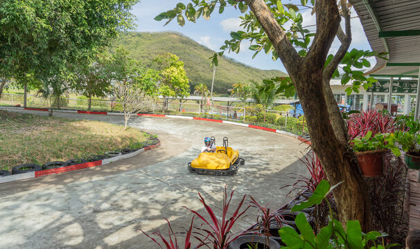 Location photos Semi-circular go-kart track A yellow two-seat go-kart with one driver is traveling on a road course. The island in the middle of the road is planted with green grass. 
