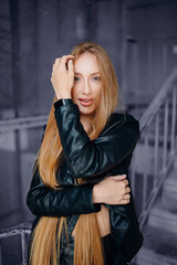 Fototapeta premium Beautiful young red-haired long-haired woman in black leather shirt
