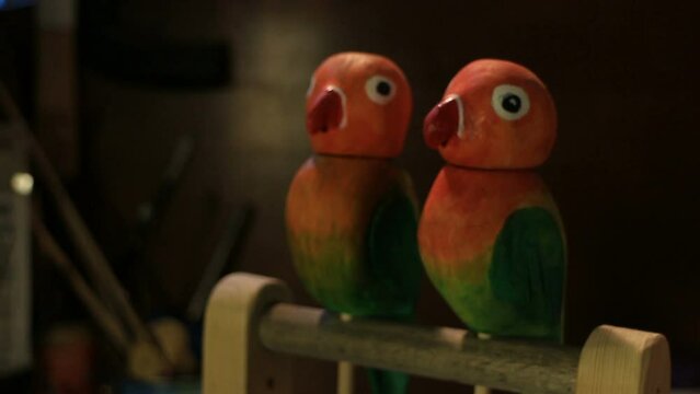 A pair of bright lovebirds, a wooden comic toy automaton, workshop interior