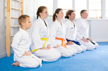 Team of family martial arts athletes is posing in gym with coach. Preparation for competitions, sports as way of life.