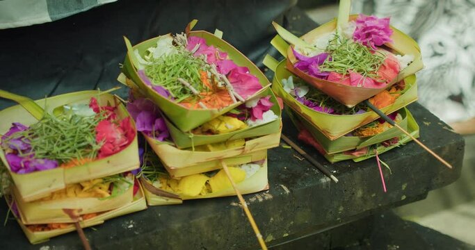 Wicker baskets with flowers and burning incense sticks. Canang Sari daily offerings made by Balinese Hindus to thank God Deva in praise and prayer.