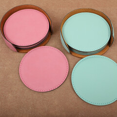 Leather table mats in teal and pink colors. Concept shot, top view. Custom background view of leather table coaster. Stitched and leather table coaster