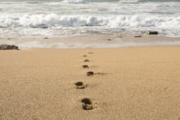 Footprints in the sand lead toward a turbulent stormy sea, suicide concept